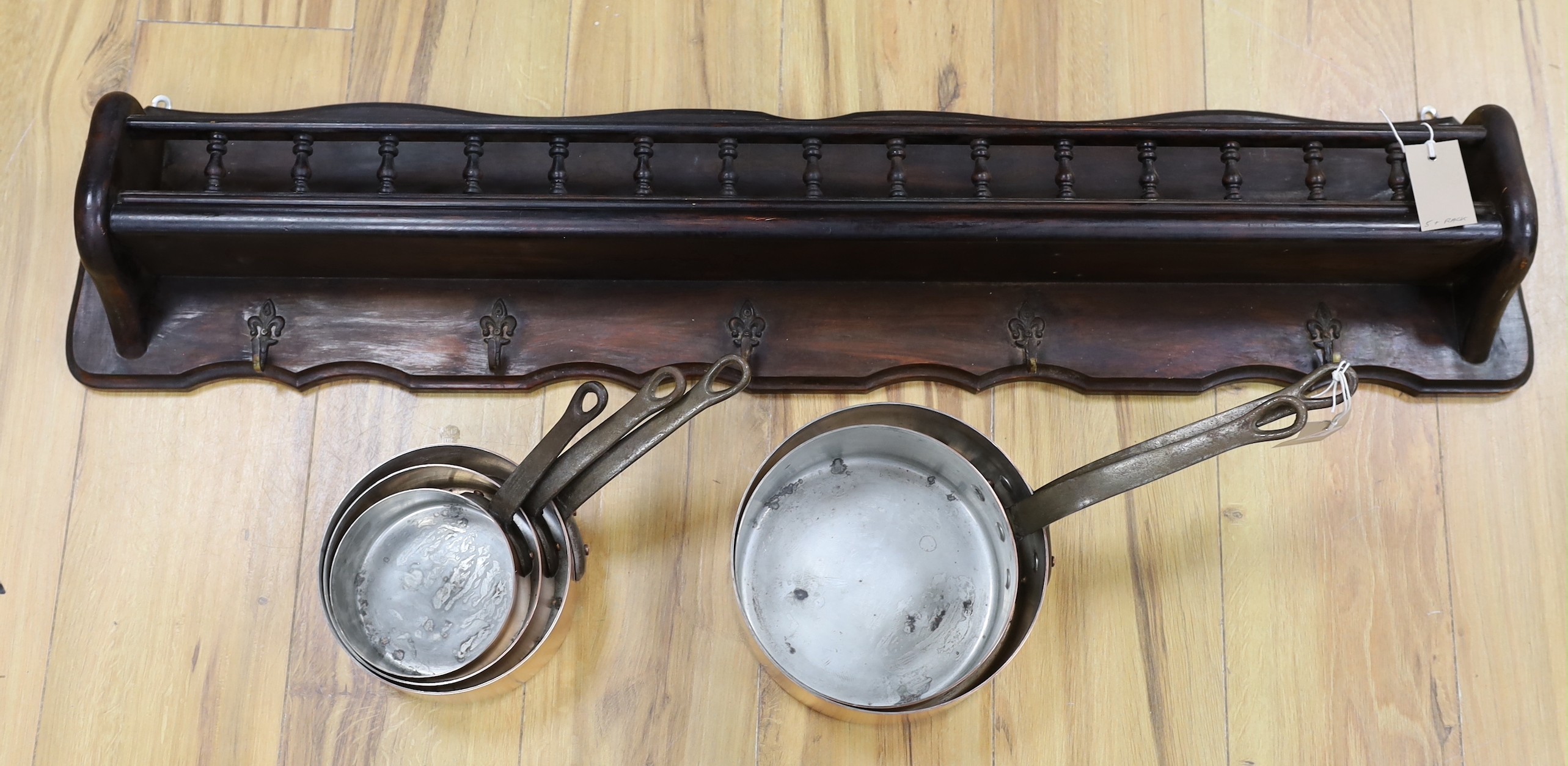 A set of five French copper saucepans, pendant from rack, rack 103cms long